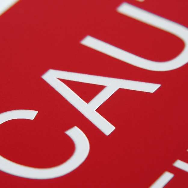Close up of white laser-engraved text with red background