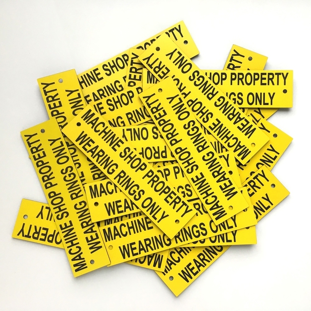 Pile of yellow/black custom informational plaques with mounting holes