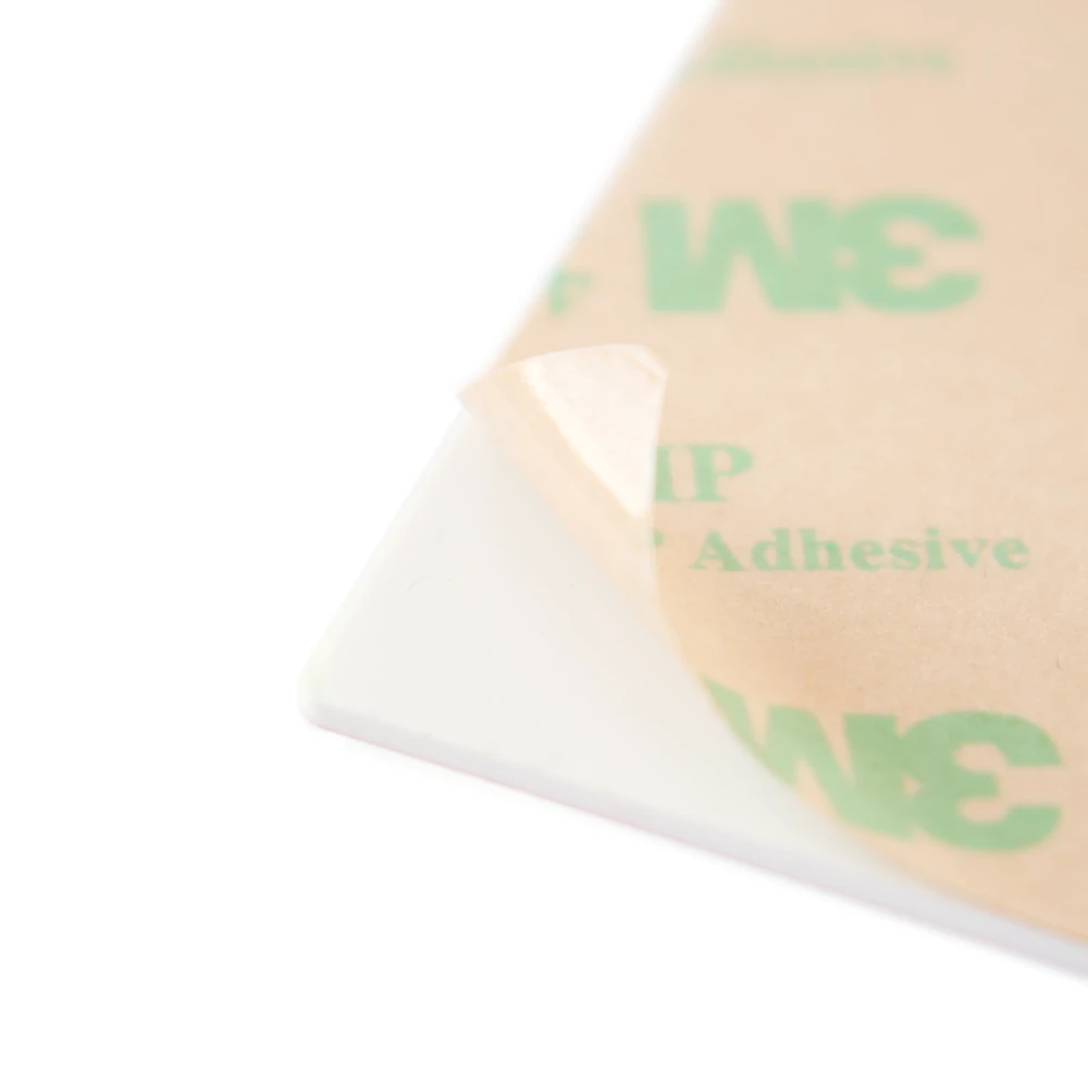 Corner of the back of a placard, showing applied adhesive with paper liner peeled back