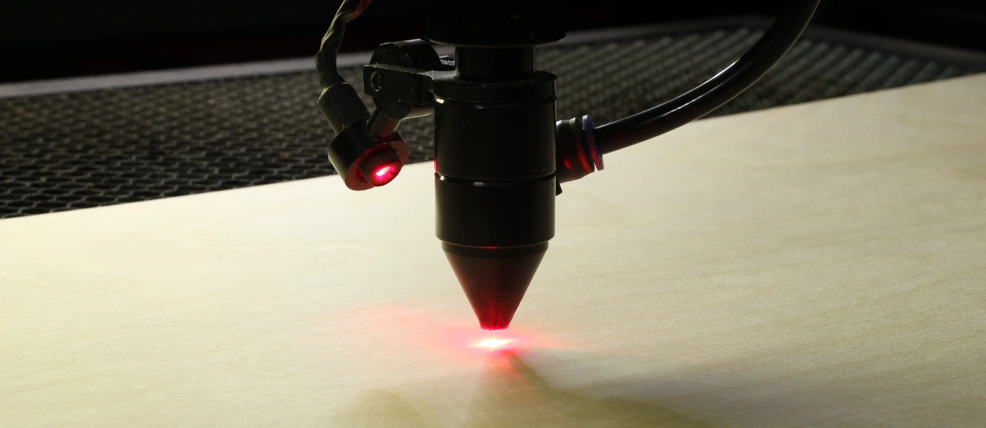 Laser head on standby positioned above plywood sheet